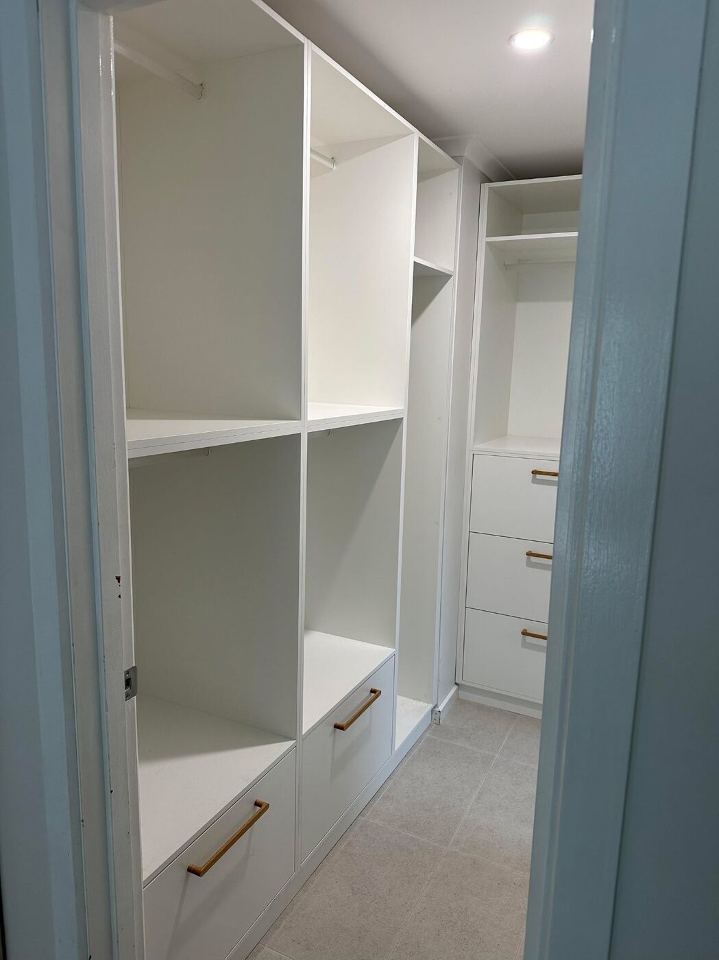 Walk-in wardrobe with open shelving, hanging rails and timber-handle drawers