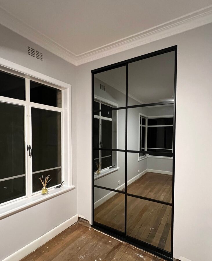 Custom wardrobe with smoked glass and mirrored sliding doors installed by Baldeco for Jon